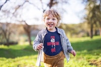 a young boy wearing a t - shirt that says i'm an american kid